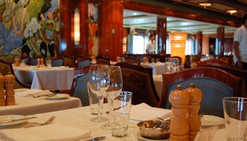 Steigt man die Stufen zum Grand Pacific Restaurant hinab, fühlt man sich wie auf einer Reise in die Zeit der historischen Ocean Liner. Das Hauptrestaurant befindet sich am Heck auf Deck 6. Durch die eindrucksvolle Glasfront speisen Gäste hier mit Meerblick © Melanie Kiel